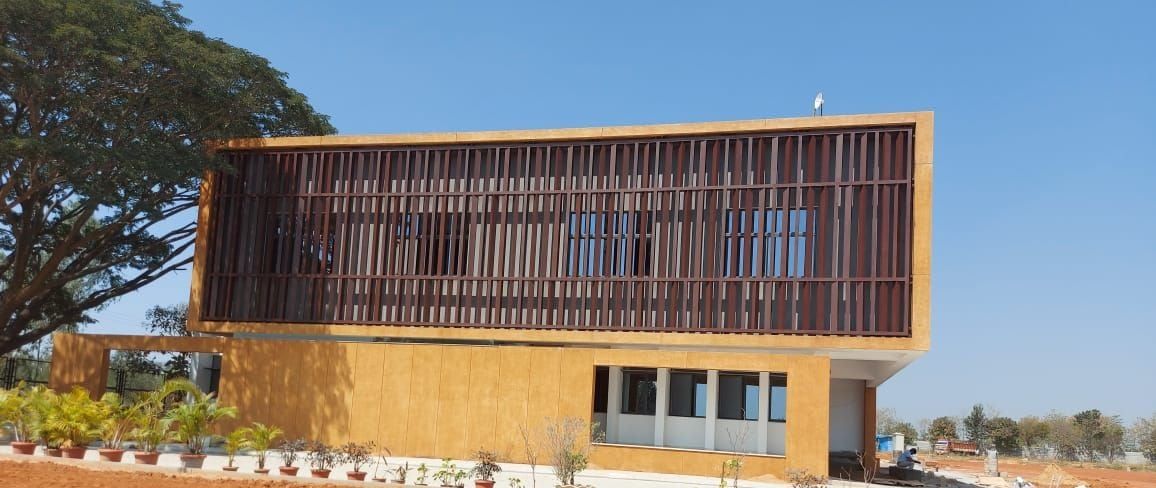 The upper floor wrapped in vertical fins, inside its frame — Basil Wood International, Gunjur, Karnataka