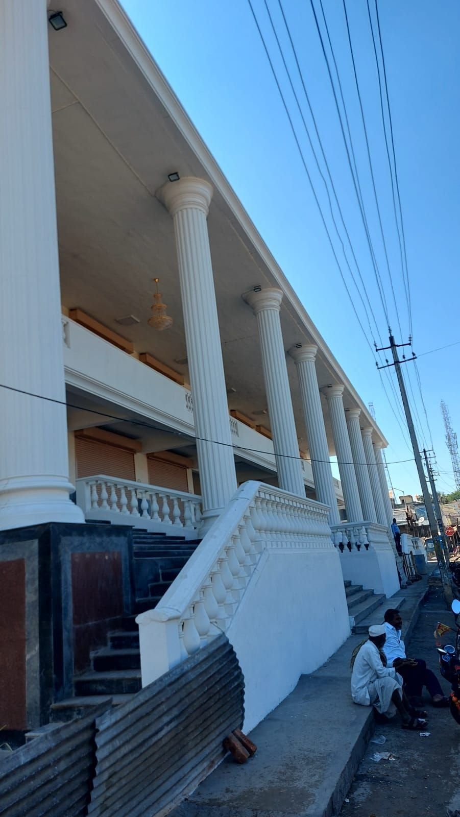 The verandah: columns along the front and the balustrade at the edge — Janatha Bazar, Basavana Bagewadi, Karnataka