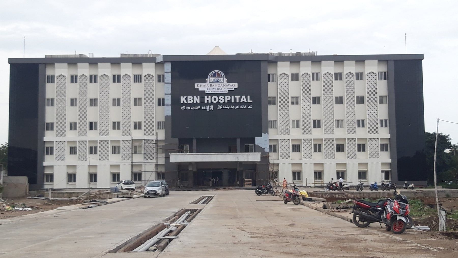 The hospital front, with arch-headed jali panels between the windows of both wings — KBN Hospital, Kalaburagi, Karnataka